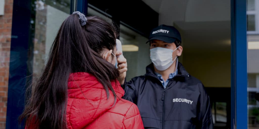 Agent Wewatch Security prenant la temperature d'une femme devant un hôpital
