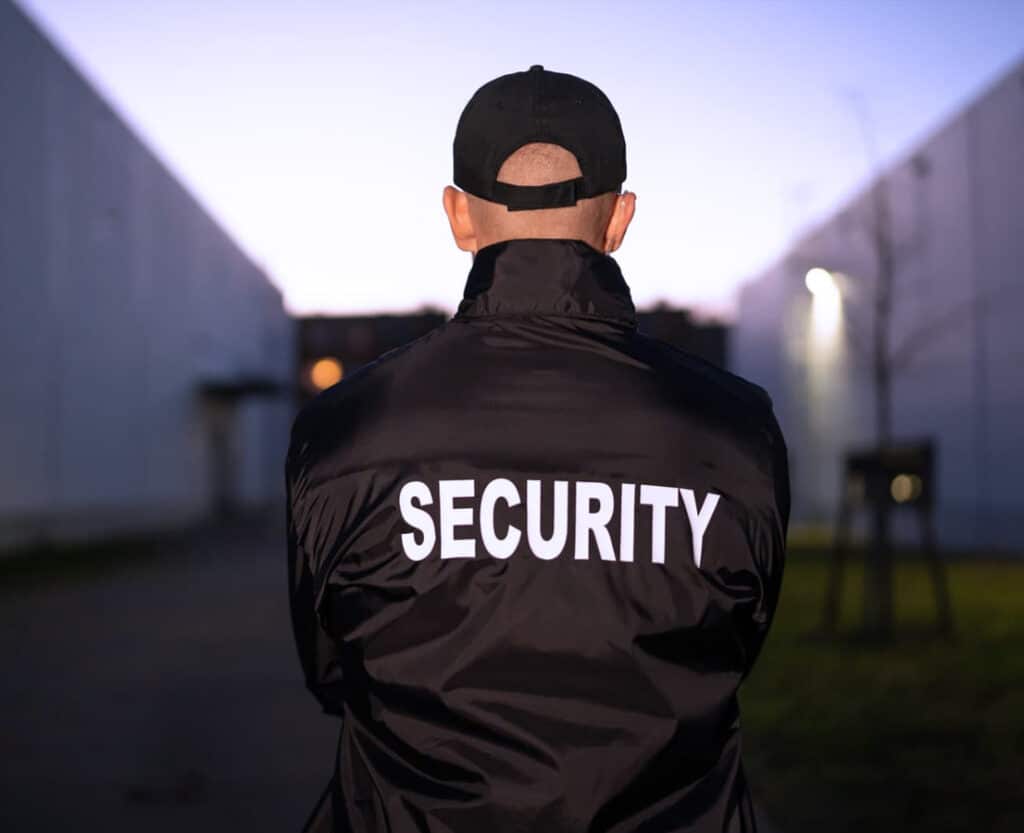Agent de gardiennage de dos surveillant la construction d'un buiding industriel.