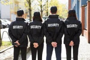 Quatre jeunes agents de gardiennage en uniforme participent a une surveillance en extérieur.