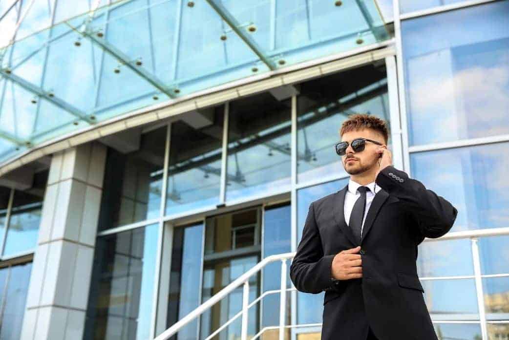 agent de sécurité en costume devant l'entrée d'une entreprise.