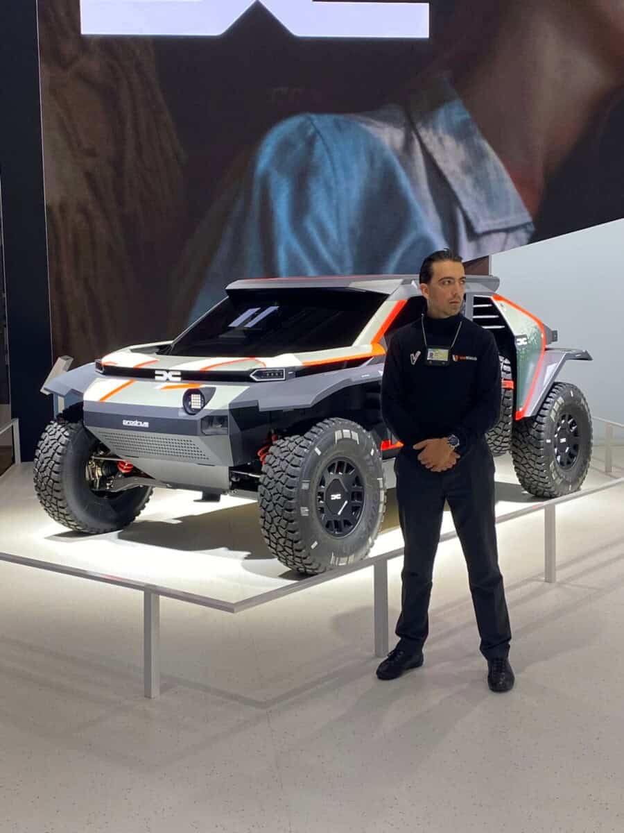 Agent WeWatch Security en uniforme surveille un véhicule de type prototype lors d'un salon automobile.